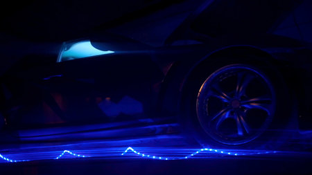 A neon-illuminated car. Clip.A bright black car with neon color around and purple headlights that change color.の写真素材