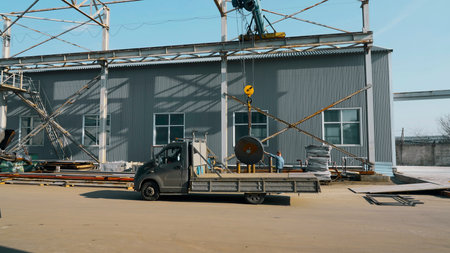 Technician worker using hoist crane for lifting metal detail in workshop factory. Creative. Work process and machinery.の写真素材
