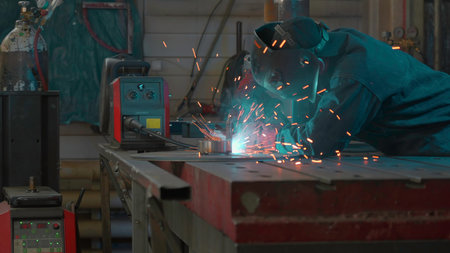 Welder in mask and working uniform working on metal structure. Creative. Man in mask with welding...