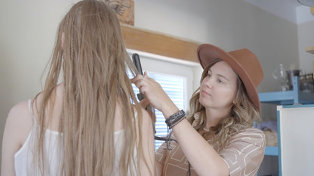 Female stylist does models hairstyle. Action. Cute hairdresser does womans hairstyle for photo...