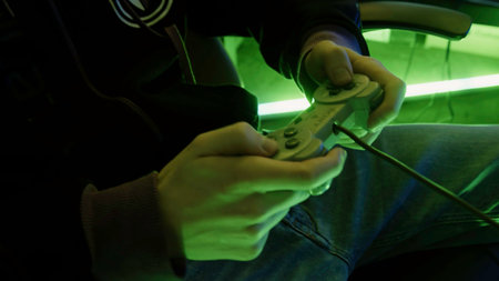 USA - New York, April 15, 2023: Close up of man gamer hands holding joystick for console. Stock footage. Young gamer sit on couch at living room with neon green lighting.のeditorial素材