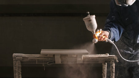 Delhi, India - April 29, 2023: Close-up of man spray painting board in workshop. Creative. Epic...