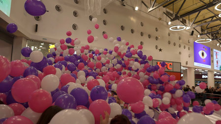 Usa - New York, May 3, 2023: Many pink and lilac air balloons falling down on people crowd in a shopping center. Clip. Opening of a shopping mall.のeditorial素材