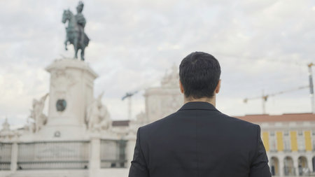 Handsome man in suit walks down street on summer day. Action. Attractive man in suit goes on date or event. Elegant man in suit walks confidently down streetの写真素材