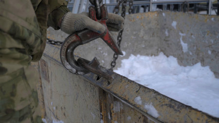 Close-up of builder hooking hook to load. Clip. Fixing hook to lift load. Hook trailer to heavy load for lifting by craneの写真素材