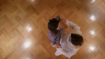Pair dancing indoors. Stock. A young couple in outfits dancing in a quiet home atmosphere holding hands.の写真素材