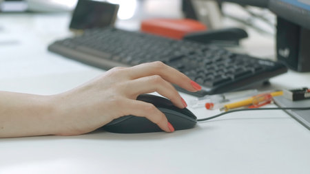 Close-up of woman working at computer in office. Creative. Woman drives computer mouse at desk. Womans hand with manicure howls with computer mouseの写真素材