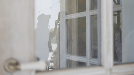 Reflection of women doing makeup. Action. Reflection in window with women preparing to shoot. Reflection in window with woman painting model before shootingの写真素材