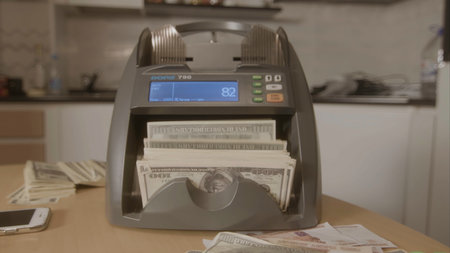Electronic money counter machine is counting the dollar banknotes. Footage. Automatic money counting in the machine.の写真素材