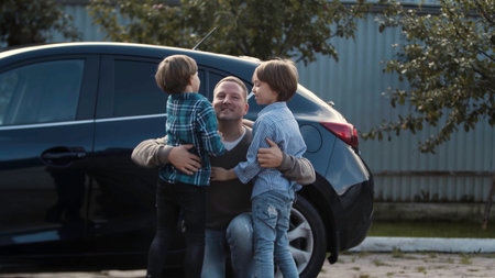 Father meets his little boys near his car outdoors. Stock. Concept of happy family and fatherhood.の写真素材