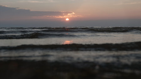 Close-up of beautiful small waves. Creative. Coastal rolling waves with solar reflection of rays. Evening tide waves with light breezeの写真素材