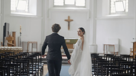Beautiful newlyweds in church. Action. Elegant couple of newlyweds walk down aisle. Beautiful newlyweds at wedding ceremony in churchの写真素材
