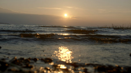 Close-up of small waves on background of sunset. Creative. Rolling small waves on seashore with...
