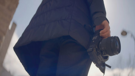 Close-up of photographer holding professional camera. Action. Camera is in hands of professional...
