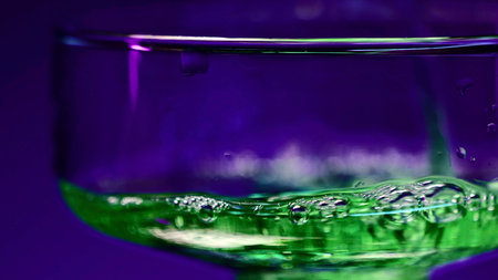 Close up of pouring green alcohol cocktail beverage in a glass at the night club. Stock clip. Concept of alcoholism and bad habits.の写真素材