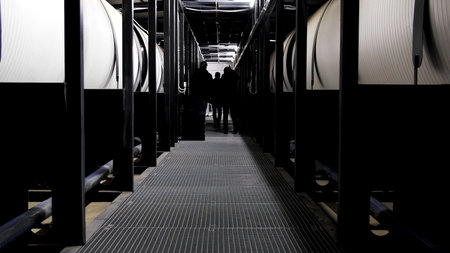 Rear view of three men walking along water treatment tanks at the power plant. Media. Corridor with huge reservoir tanks for water purification, ecology concept.の写真素材