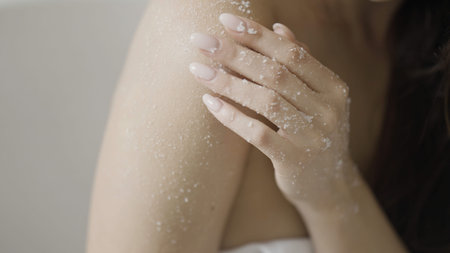 Bodycare concept, sensual woman applying scrub on her body. Action. Sugar scrubbing of her shoulder...