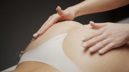 Close-up masseur rubs scrub. Action. Scrubbing and massage for body elasticity. Elastic buttocks with massage and scrub. Spa salons.の写真素材