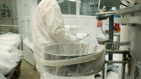 Putting flour inside the special container at the baking factory. Clip. Worker making dough at the...
