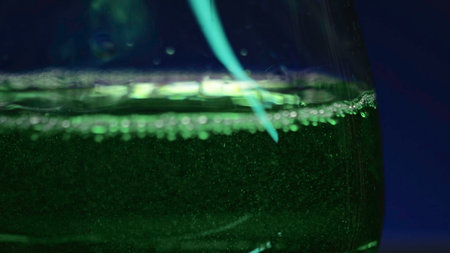 Close-up of drink being poured into transparent glass. Stock clip. Green alcoholic drink is poured into glass. Club drinks in glass on isolated background.の写真素材