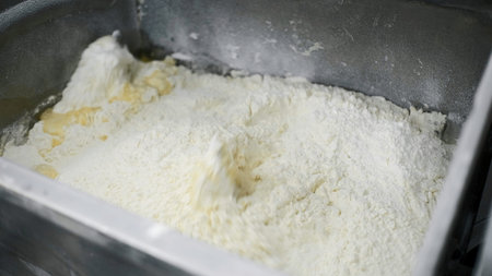 Preparation of dough in industrial machine. Clip. Close up of automatic mixing ingredients for dough...