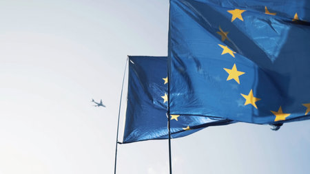 Close-up of people holding the European Union Flags waving in the wind against the blue sky....