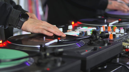 DJs play records at the disco. Art. Close-up of DJ's hand on the mixer. Glowing music panel at a...