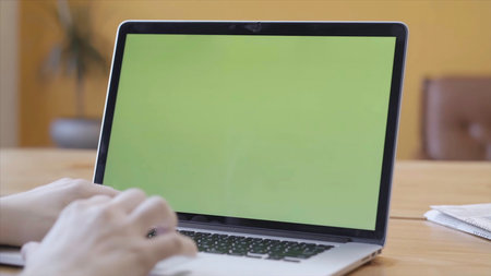 Woman's hands with perfect manicure typing on a laptop keyboard. Chroma key green screen for placement of your own content.の写真素材