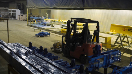 Loader carries parts in factory. Clip. Forklift truck carries heavy spare parts in factory warehouse. Loader for transport of heavy goods in warehouses.の写真素材