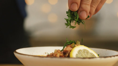 Close-up of some person's hand adding greens at the bowl with solyanka. Russian solyanka soup with meat, sausages and olivesの写真素材