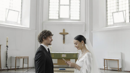 The wedding vow in the church. Action.The newlyweds standing in a large temple decorated with crosses and give each other an oath.の写真素材
