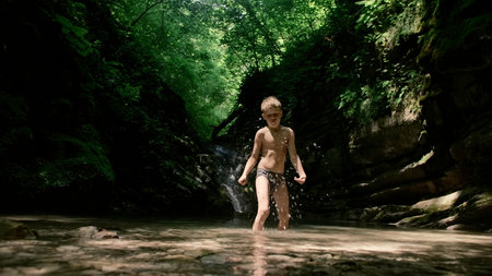 A child on a journey. Creative. A little boy in underpants playing in the water and large rocks from...
