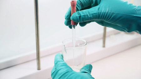 Close up of transparent liquid being poured into a bottle with a pipette on a white background....