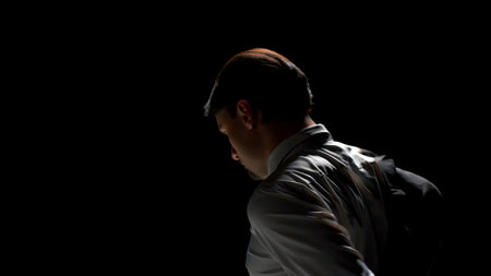 Rear view of attractive man putting on suit. Stock footage. Man takes jacket from chair and puts it on in front of mirror. Man wears costume on theatrical stage in single productionの写真素材