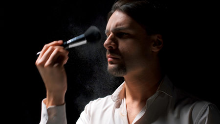 Man applies powder to his face with brush. Stock footage. Man puts powder on face on theater stage....