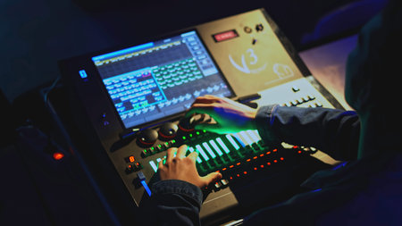 Light console control. Media. Man moves joysticks on light and sound control panel in theater....