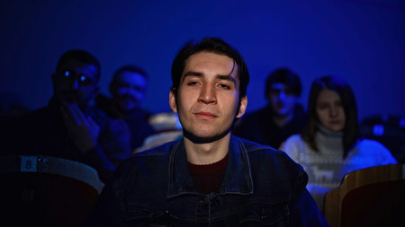 Audience at theatre or cinema. Media. Portrait of a man and silhouettes behind applauding.