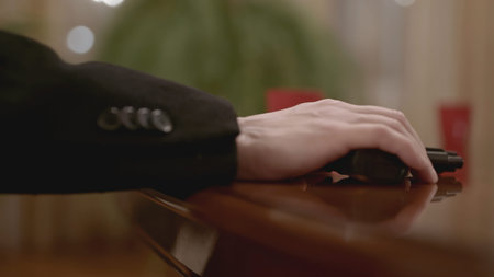 Close-up of thug holding gun. Stock. Man holds gun on table and threatens. Thug threatens with gun...
