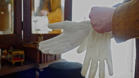 Close up of man in classic clothes putting on satin gloves. Stock footage. Retro background with antiques.の写真素材