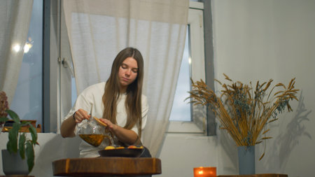Young woman romantically drinks tea in cafe. Media. Young female student is relaxing in cafe with tea. Beautiful young woman is drinking tea alone in cozy cafeの写真素材