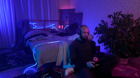 Man using smartphone and listening to music at home. Media. Cozy and messy room of a hipster guy.