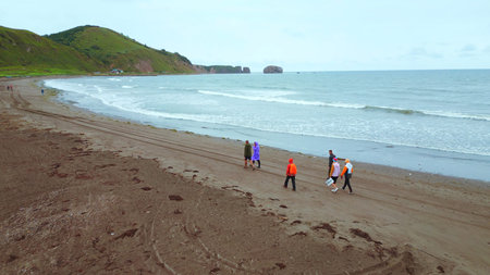 Top view of people by sea with mountain view. Clip. Coast with walking people and amazing mountains on cloudy day. Walk on mountain coast of ocean on cloudy dayの写真素材