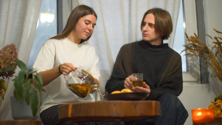 Young man and woman are talking over tea in cafe. Media. Young couple of students are talking with tea in cozy cafe. Couple on student break with tea and comfortable conversationの写真素材
