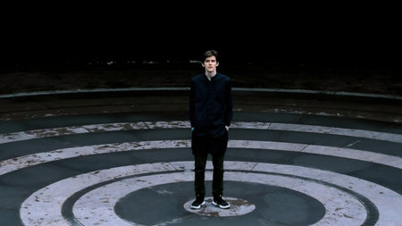 Tall man in black clothes standing in the meddle of amphitheater. Stock clip. Asphalt colored in...