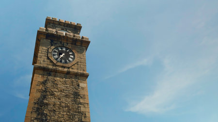 Historic clock tower with picturesque clouds and blue sky on the background. Action. Low angle view of the ancient brick tower.の写真素材