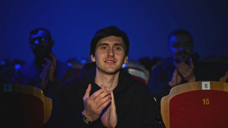 Young man is watching concert and applauding. Media. Young man is watching theater concert....