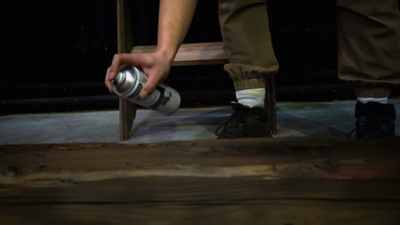 Man painting wooden beam, close up. Media. Man worker using black color spray paint for painting the...