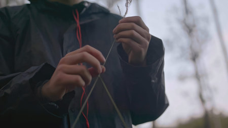 Close-up of man holding straw in forest. Stock. Young man walks in forest and tears up grass. Man...