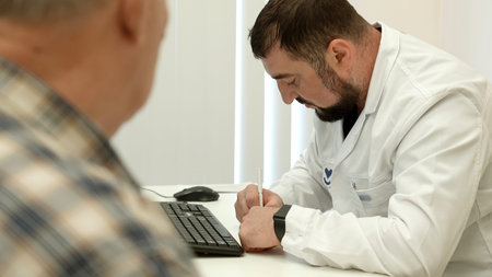 Male doctor working at the table, writing prescription. Clip. Old male patient at the hospital.の写真素材