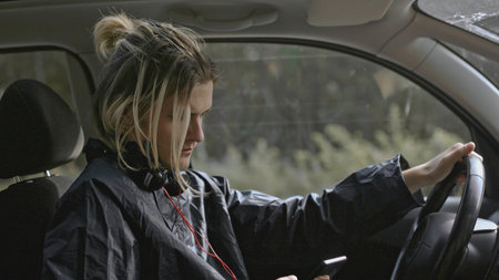 Young man worries and looks at phone in car. Stock. Man looks at phone during nervous breakdown in...